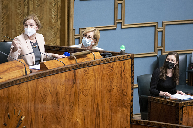 Eduskunnan lainsäädäntöjohtaja, työministeri ja pääministeri katsovat kohti puhemiestä, joka ei näy kuvassa.